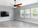 Spacious living room with stylish wood floors, three bright windows, and a mounted TV at 2720 Watergarden St, York, SC 29745