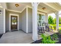 Detailed front door with a floral wreath, complemented by rocking chairs on the covered porch at 3041 Winged Teal Ct, Belmont, NC 28012
