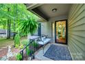 Inviting covered front porch features a cozy bench, decorative rug, and lush greenery at 353 Tall Oaks Trl, Fort Mill, SC 29715
