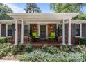 A close-up view of the home's cozy front porch, decorated with green chairs and a charming wreath on the door at 5640 Sharon Rd, Charlotte, NC 28210