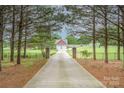 Long driveway lined with mature trees leads to a charming home with a large lawn at 8993 Plank Rd, Norwood, NC 28128