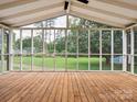 Spacious screened porch with wood floor and white trim offering scenic backyard views at 10728 Forest Dr, Matthews, NC 28105