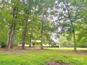 Ranch style home with light yellow paint, surrounded by mature trees on large lot at 1614 Medlin Rd, Monroe, NC 28112