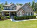 Inviting two-story home featuring a stone and brick facade, covered porch, and well-maintained landscaping at 16547 Bastille Dr, Charlotte, NC 28278