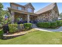 Charming home with a stone facade, inviting covered porch, and lush landscaping for a cozy curb appeal at 16547 Bastille Dr, Charlotte, NC 28278