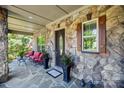 Relaxing front porch with stone facade, comfortable seating, and decorative planters adding charm and appeal at 16547 Bastille Dr, Charlotte, NC 28278