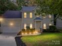 Inviting two-story home with landscape lighting enhancing its charming facade and well-maintained front yard at dusk at 216 Devon Forest Dr, Mooresville, NC 28115