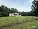 Expansive lawn surrounds a well-kept single-story home nestled among mature trees providing a private setting at 40287 Palmerville Rd, New London, NC 28127
