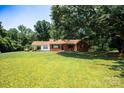 Well-manicured front lawn showcasing a classic brick home with mature trees and covered entry at 7016 Tirzah Rd, Waxhaw, NC 28173
