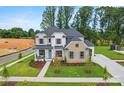 Beautiful home with a manicured lawn and landscaping, featuring a stone and painted brick exterior with a charming front porch at 14011 Camden Close Cir # 25, Huntersville, NC 28078