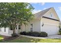 Charming home featuring a two-car garage, well-manicured lawn, and a mature, flowering tree in the front yard at 1471 River Bend Blvd, Indian Land, SC 29707