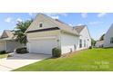 View of the home's garage with a dark accent above and a lovely landscaped lawn space at 1471 River Bend Blvd, Indian Land, SC 29707