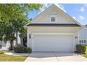 View of the home's clean garage with a dark accent above and a lovely landscaped lawn space at 1471 River Bend Blvd, Indian Land, SC 29707