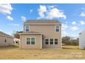 A rear view of the home featuring a neutral siding, good-sized backyard, and a glimpse of surrounding trees at 219 Parker Claire Ln, Kings Mountain, NC 28086