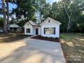 Inviting single-story home featuring white siding, black shutters, and a new concrete driveway at 219 Pine St, Rockwell, NC 28138