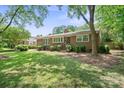 Traditional brick home featuring a beautiful lawn, mature trees, and classic architectural details at 3612 Trent St, Charlotte, NC 28209