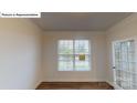 Bright room showcasing hardwood floors, paneled walls, a large window and a glass paneled door at 7190 Sylvan Retreat Dr, Denver, NC 28037