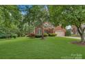 Brick home with lush, mature landscaping, a long driveway, and a two-car garage at 9040 Scottsboro Dr, Huntersville, NC 28078