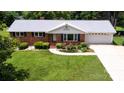 Brick home boasting a well-kept lawn, flower beds, and a spacious driveway leading to a garage at 1216 Manchester Ln, Charlotte, NC 28227