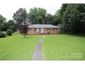 Brick home featuring a well-manicured lawn and inviting walkway to the front door at 1227 Flowe Dr, Matthews, NC 28104