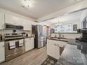 Bright kitchen features white cabinets, stainless steel appliances, granite countertops, and wood-look tile flooring at 1252 Winding Path Rd, Lake Wylie, SC 29710