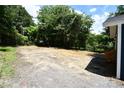 View of a large empty, partially cleared lot showing the side of the blue painted home at 1406 Caldwell St, Gastonia, NC 28052