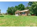 Charming brick home with a metal roof, a white porch, black shutters, and a spacious green front yard at 142 Single Oak Dr, Troutman, NC 28166