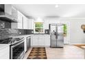 Bright kitchen features stainless appliances, white cabinets, gray tile backsplash, and tile flooring at 2919 Dunaire Dr, Charlotte, NC 28205