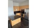Bright kitchen featuring an island with granite countertops, stainless steel appliances, and wood cabinetry at 333 W Trade St # 505, Charlotte, NC 28202