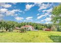 Charming one-story home featuring a red roof, green lawn, and several outbuildings at 439 Neisler Rd, Concord, NC 28025