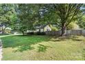 This house showcases a spacious grassy yard with mature trees and a wooden fence at 5229 Milford Rd, Charlotte, NC 28210
