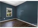 Cozy bedroom painted navy blue and featuring hardwood floors and a sunlit window at 556 Big Lick Rd, Stanfield, NC 28163