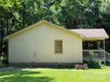 Side view of a light yellow home with a brick foundation and a covered porch, showcasing its simple design at 5881 Robinhood Rd, Fort Lawn, SC 29714