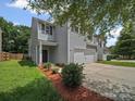 View of home with a two car garage, landscaping, and small front yard at 6803 Ware Rd, Charlotte, NC 28212