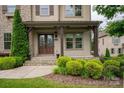Inviting front porch with stone steps, dark wood pillars, and lush green landscaping at 1233 Ladera Dr, Waxhaw, NC 28173