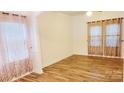 Bright living room with wood-look floors, neutral walls, and modern curtains offering natural light at 12450 Stone Garden Dr, Huntersville, NC 28078
