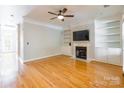 Bright living room featuring hardwood floors, fireplace, built-in shelves, and ceiling fan at 14222 Richmond Park Ave, Charlotte, NC 28277