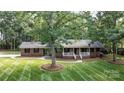 Attractive brick home featuring a well-kept lawn with mature trees and inviting covered porch at 4323 Crow Rd, Monroe, NC 28112