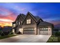 Stunning two-story home with a stone and brick exterior, twilight, and a long driveway to the garages at 837 Kathy Dianne Dr, Indian Land, SC 29707