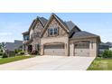 Stunning two-story home with a stone and brick exterior and a long driveway to the garages at 837 Kathy Dianne Dr, Indian Land, SC 29707