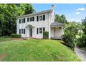 Traditional home featuring black shutters, white siding and a covered porch set amid lush greenery at 904 Edgewood Cir, Gastonia, NC 28052