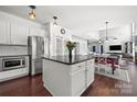 Modern kitchen with stainless steel appliances, an island with dark countertop, and an open view into the dining and living area at 9429 Coast Laurel Nw Ave, Concord, NC 28027