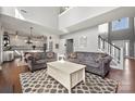 Open-concept living room boasts hardwood floors, stylish sofas, bright light, and view into kitchen and stairway at 9429 Coast Laurel Nw Ave, Concord, NC 28027