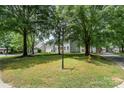 Street view of home with mature trees, grassy median and street signage at 12411 Herdon Ct, Charlotte, NC 28277