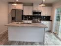 Stylish kitchen with white cabinets, stainless steel appliances, island, and dark backsplash at 126 Zircon Dr, Statesville, NC 28625