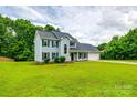 Traditional two-story home with a lush green lawn, complemented by mature trees and blue siding at 12812 Bradford Hill Ln, Huntersville, NC 28078