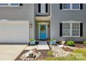 Inviting front entrance with a blue door, decorative wreath, potted plants, and stone landscaping at 2090 Durand Rd, Fort Mill, SC 29715