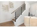 Modern staircase featuring hardwood floors, white risers, and a sleek metal railing at 2523 Irwin Stream Rd, Charlotte, NC 28208