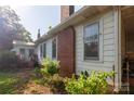 Rear exterior shows the brick chimney, a small back porch, and greenery around the home at 3220 Harmony Hwy, Harmony, NC 28634