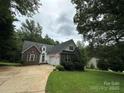 Inviting brick home with attached garage, mature trees, and an American flag at 613 Stacy Ridge Rd, Gastonia, NC 28052